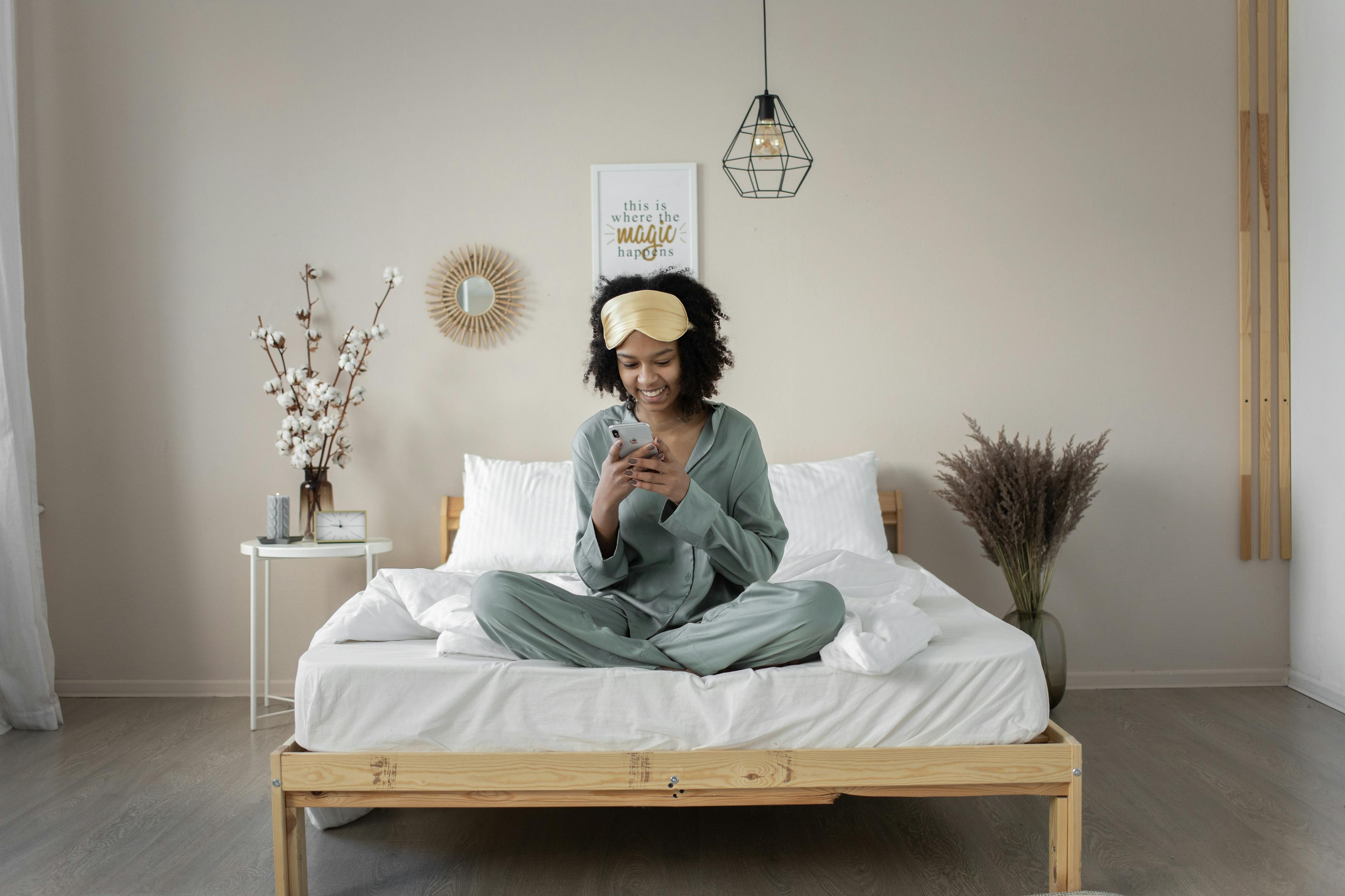 woman on bed playing mobile phone